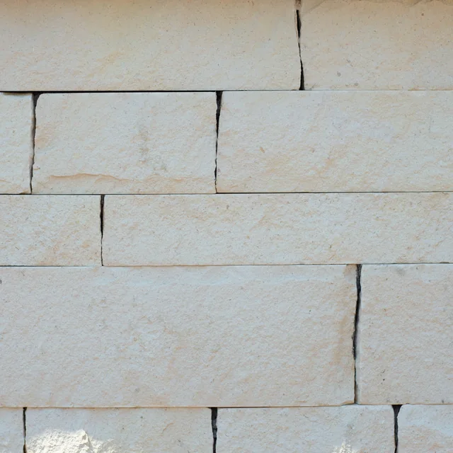 Pale cream Ivory White limestone blocks with subtle warm bands and close dry-stack joints.