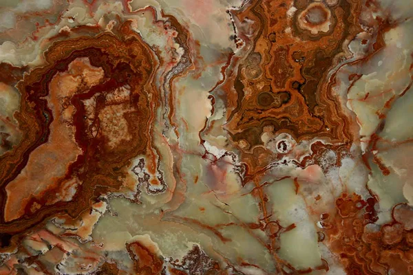 Grand Canyon Onyx with rust-red and brown bands around pale green and cream areas.