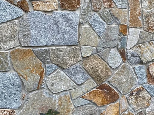 Weymouth Granite mosaic thin stone veneer showing blue-gray, gold and brown faces.