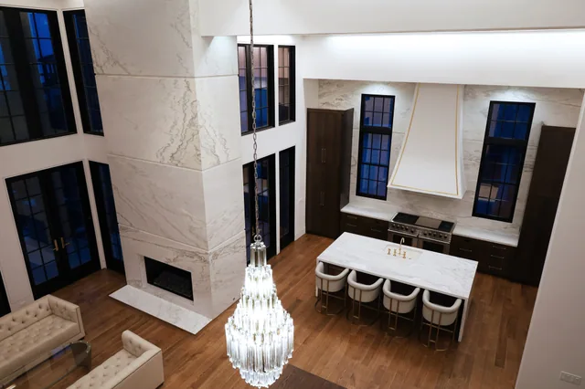 Double-height residence with a Silver Cloud marble fireplace and kitchen island.